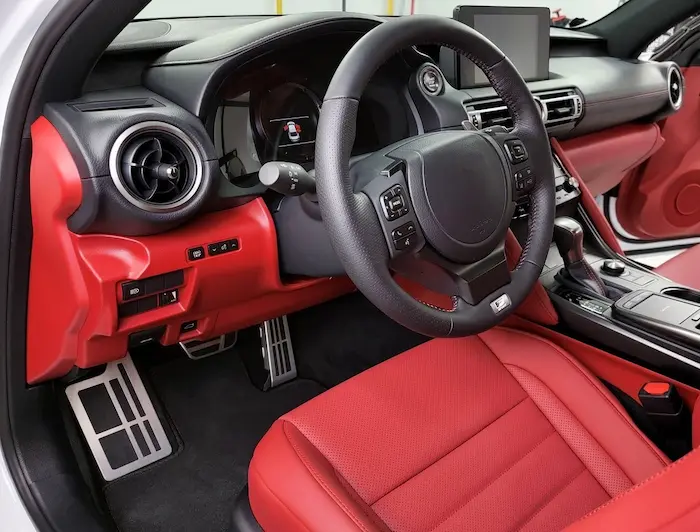 atelier de detailing auto cu mașină pe rampă, tehnician care lucrează la polisare și echipamente profesionale în fundal